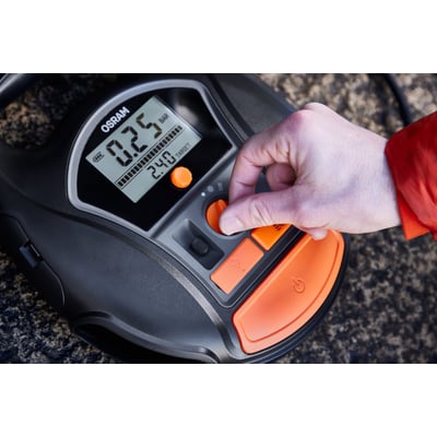Nærbillede af Osram TYREinflate 6000 dækoppumper, med en finger der justerer trykket på den digitale skærm.