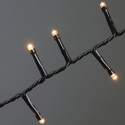 Konstsmide lyskæde med 1000 ravfarvede LED'er og sort plastikkabel, vist på grå baggrund.