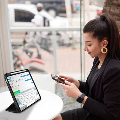 Kvinde bruger 4smarts Folio Case Basic til iPad på en café, med pen og telefon ved siden af.