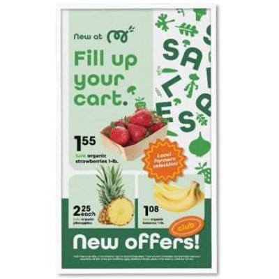 Samsung EM32DX 32-tommers E-Paper-skærm viser en grøn dagligvareannonce med tilbud på jordbær, ananas og bananer.