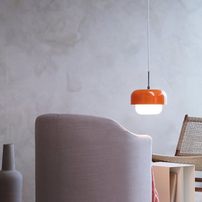Haipot pendel i orange fra Dyberg Larsen monteret i et moderne rum med møbler og dekorationsgenstande.