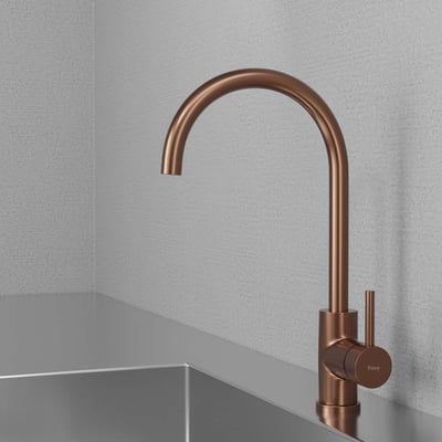 Lavabo Primy Curve køkkenarmatur i ravfarvet kobber, monteret ved en stålvask i et moderne køkkenmiljø.