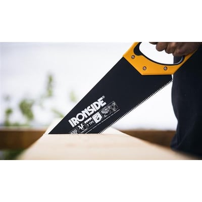 Ironside håndsav med sort 550 mm klinge og gult håndtag bruges til at save i et stykke træ.