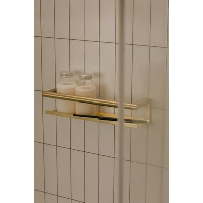 Cosmic brusehylde i børstet guld med to flasker og en glasvisker, monteret på flisevæg.