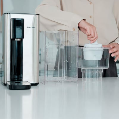Philips vandedispenser ADD5906S/10 i rustfrit stål med en person, der isætter et filter i vandtanken.