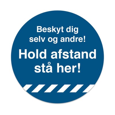 Blåt rundt gulvskilt med hvid tekst "Beskyt dig selv og andre! Hold afstand - stå her!" og hvide skråstriber nederst.