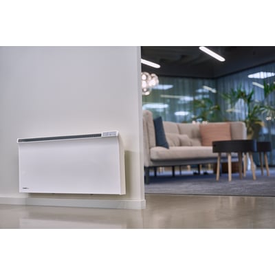 Glamox Termostat WT3 WiFi monteret på væg i et moderne kontormiljø med sofa og planter i baggrunden.