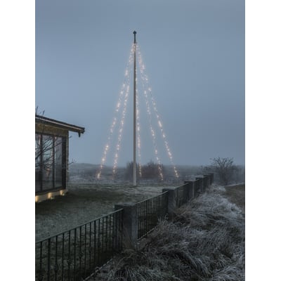Konstsmide flagstangskæde med 500 lys, installeret på en flagstang i tåget vejr, med et hus i baggrunden.