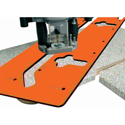 Fræseskabelon i orange plast anvendes til præcis bordsamling med en fræser monteret på skabelonen.