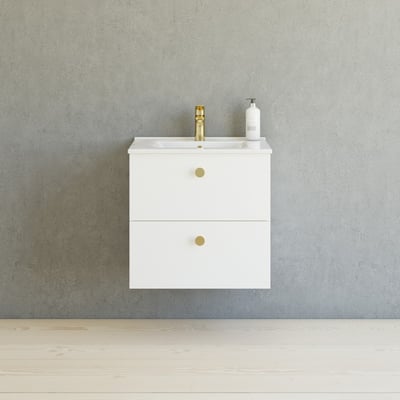 Dansani Button greb i messing med sort finish, vist på et hvidt møbel med en messingvandhane og grå væg.