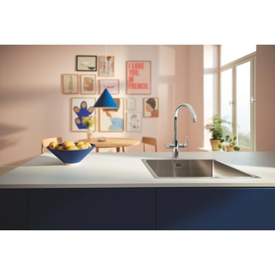 Grohe Blue Pure Startcurve etgrebsbatteri i krom med C-tud monteret ved en køkkenvask med en skål frugt.