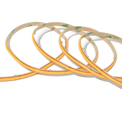 COB-LED-strip Anycut på 5 meter ligger i løse buer og viser den smalle, orangefarvede lysstribe.