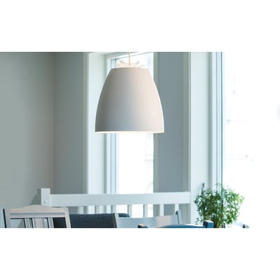 SG Armaturen Pendel Bell Mini i hvid/guld med dybtmonteret lyskilde, hængende over et spisebord i et lyst rum.