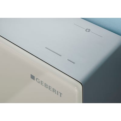 Geberit Monolith Plus cisternemodul med front i sandgrå glas og børstet aluminium.