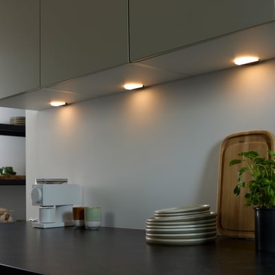 Loevschall Polaris Round LED lys med tænd/sluk sensor, monteret under køkkenskabe og oplyser køkkenbordet med varmt lys.