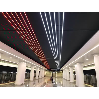 Ansell Lighting U-Cell LED strip i 6500K hvid og rød lys på en sort loftbeklædning i et moderne offentligt rum med søjler.