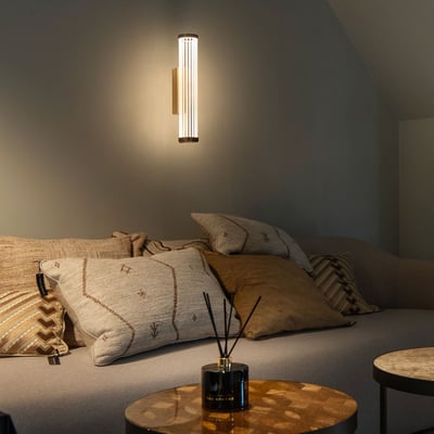SLV QUIMERA WL væglampe monteret på en væg over en sofa, illuminerer rummet med en blød og dæmpbar atmosfære.