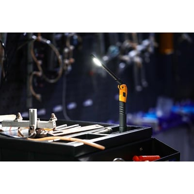 Ironside genopladelig slim mini LED-håndlampe lyser på et værkstedsbord med det justerbare lampehoved vinklet.