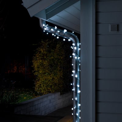 Konstsmide lyskæde med 80 hvide LED monteret på tagrende udendørs om natten.