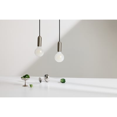 To Osram Ledvance LED globe 95 lyskilder hænger ned fra sorte ledninger, med dekorative elementer som små grønne blade og et lille metalkopper på et hvidt bord.