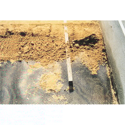 Expo-net armeringsnet 1211L påbegyndt monteret på sandet underlag med en vaterpas og grus foran.