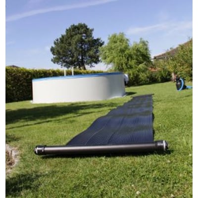 Swim & Fun solvarmepanel på 6,1 x 0,6 meter ligger rullet ud på græsset ved siden af en pool på en solskinsdag.