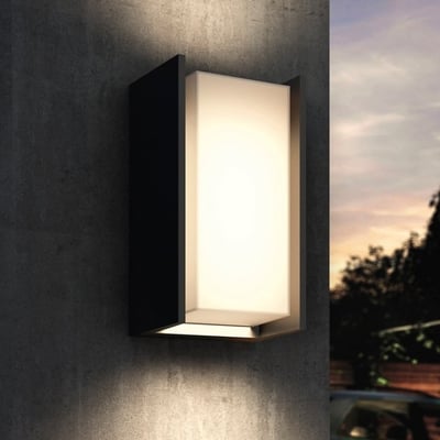 Philips Hue Turaco udendørs væglampe i antracit lyser varmt hvidt på en udvendig væg ved skumring.