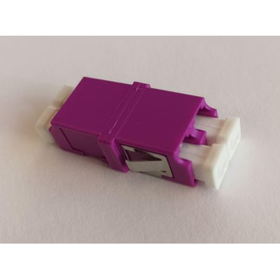 Adapter OM4 LC/PC Duplex i lilla med SC footprint og uden flange. Den har hvide LC-porte på hver side og et metalklemme til montering.