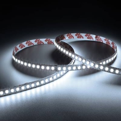 To sammenkrøllede Ansell Lighting E-Cell Eco LED bånd med hvidt lys og 3M tape bagpå, vist i mørke.