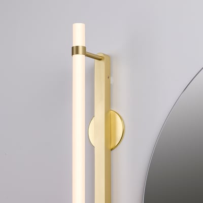 Nærbillede af samlingen på Loevschall Katana LED væglampen i messing med detaljer om monteringspladen og et rundt spejl.