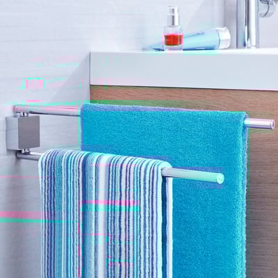 Tesa Ekkro 2-armet håndklædeholder i krom hænger to håndklæder på et badeværelsesarrangement.
