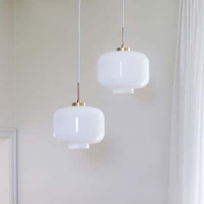 To Dyberg Larsen ARP pendler med opal glas og messing detaljer hænger side om side i en indretning.