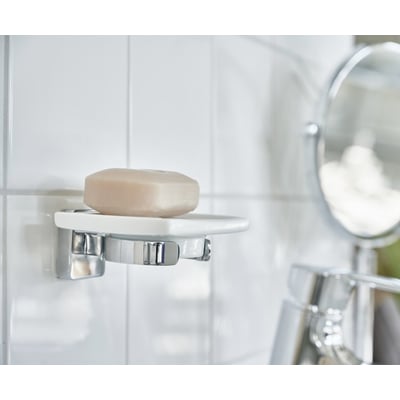 Smedbo ice vægmonteret sæbeskål i hvidt porcelæn med poleret krom detaljer, indeholdende en lys sæbe.