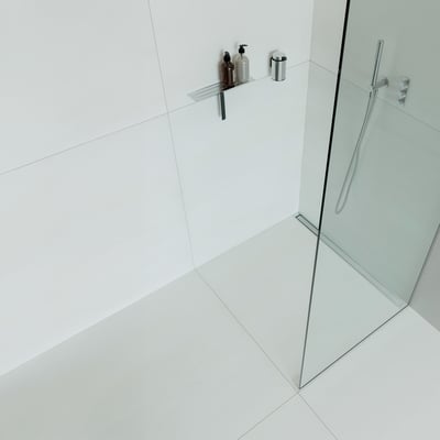 Unidrain HighLine panel på 1200 mm i håndpoleret stål, vist monteret i et moderne badeværelsesmiljø med glas brusevæg.