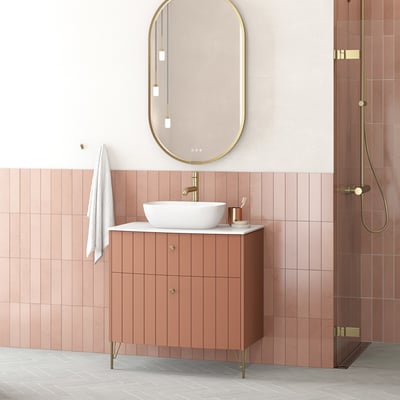 Dansani YOU støtteben i vintage messing, som et moderne element på et badeværelsesskab med rosa front og hvid bordplade.