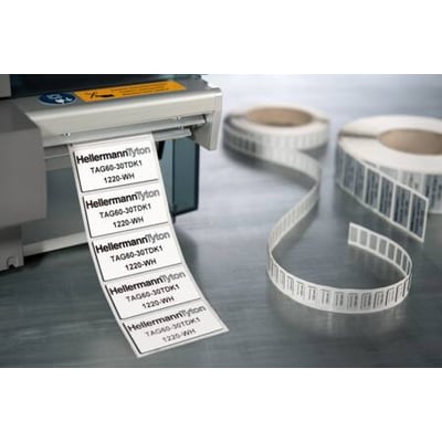 Hvide HellermannTyton-panelmærker på rulle, 45 x 15 mm, ses med trykte markeringer ved en labelprinter.