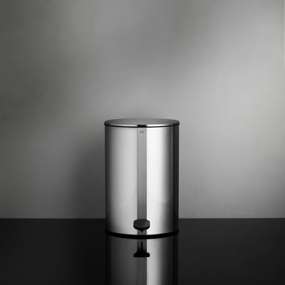 Unidrain Reframe pedalspand på 4 liter i håndpoleret stål, vist med låg lukket på sort blank overflade foran grå væg.