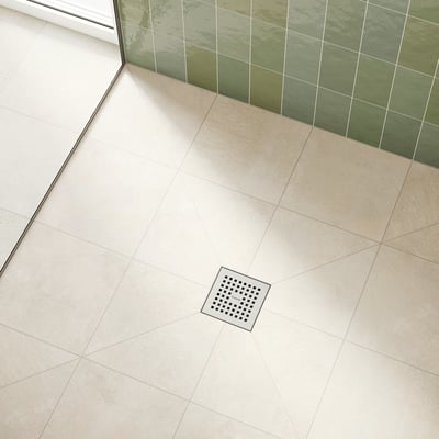 Hansgrohe afløbsskål monteret i et moderne badeværelsesgulv med lyse klinker og grønne vægfliser.