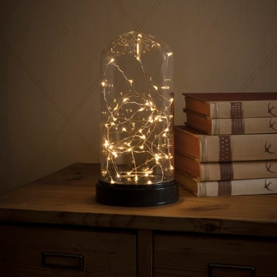 Detaljeret billede af Konstsmide glaskuppel med tændte 50 amber LED-lys, viser varm belysning på et møbel.