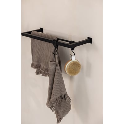 Metallbude Stenni håndklædeholder i sort metal med to bøjler og en rund børste hængende på en krog. To grå håndklæder er draperet over bøjlerne.