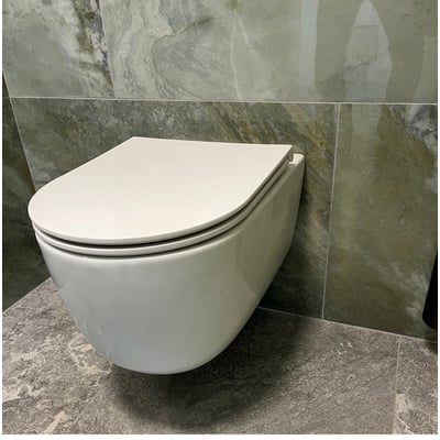 Monteret hvidt Cassøe Silent toiletsæde på en væghængt toiletkumme, indrammet af moderne badeværelsesfliser.
