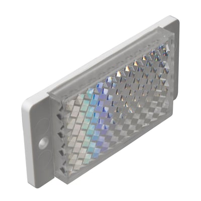 Carlo Gavazzi prismereflektor på 32,5 x 65 x 8 mm med facetteret refleksflade, set skråt forfra.