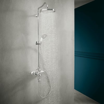 AXOR Montreux showerpipe med termostat, hovedbruser 240mm og håndbruser i krom, i funktion med vandløb mod grå baggrund.
