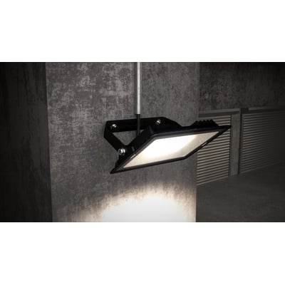 Ansell Lighting Eden LED projektør i sort, monteret på en betonvæg med lyset tændt, viser bred belysning udendørs.