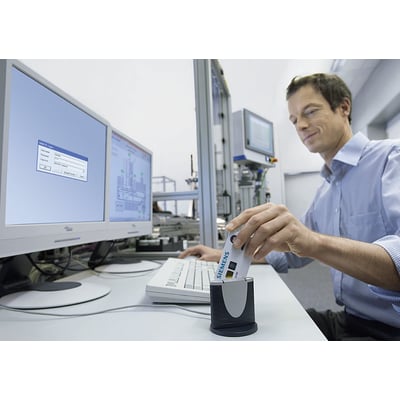 En mand bruger en Siemens SIMATIC PCS7 USB chipkortlæser til at logge ind på et computersystem, der viser et login-vindue.