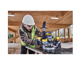 Håndværker med sikkerhedsudstyr bruger DeWalt 18V XR overfræser på træplade i et træbyggeri.