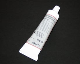 En tube af "GRAISSE SILICONE CONDUCTRICE THERMIQUE" på 200 gram, med tydelig tekst om anvendelse og producent på mørk baggrund.