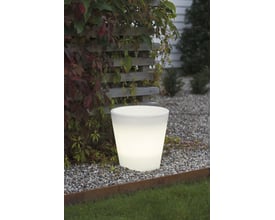 Konstsmide Assisi LED blomsterkrukke lille, hvid, oplyst om aftenen i en have med grus og planter.