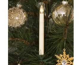 Nærbillede af Konstsmide LED juletræsbelysning i hvid plast med grøn klemme, lysende med et varmt hvidt skær.