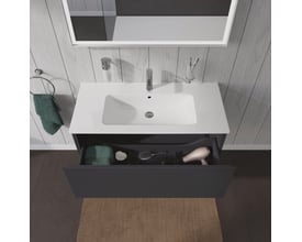 Duravit L-Cube vaskeskab i grafit mat, med skuffen åben og vist fyldt med badeværelsestilbehør som hårtørrer og børster.